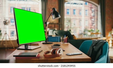 Desktop Computer With Mock Up Green Screen Display Standing On A Desk In Cozy Living Room. In The Background Stylish Modern Bright Home Office Studio During Day With Big Cityscape Window.