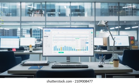 Desktop Computer Monitor with Finance Statistical Data Software and Progressive User Interface Standing on the Desk in the Modern Business Office. In the Background Glass Wall with Big City Office. - Shutterstock ID 2109008477