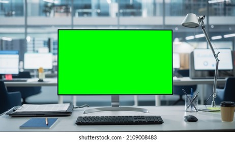 Monitor de computadora de escritorio con pantalla de croma de pantalla verde simulada colocado en el escritorio de la oficina de negocios moderna. En la pared de vidrio de fondo con la oficina de la ciudad grande.
