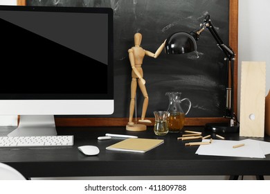 Desktop with computer monitor and other items against blackboard background - Shutterstock ID 411809788