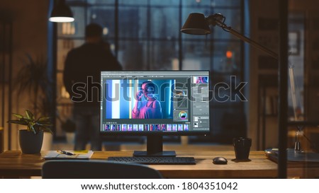 Desktop Computer with Photo Editing Software Standing on the Desk in the Modern Creative Office. In the Background Designer Drinks from a Cup Looks at the Night City out of the Window.