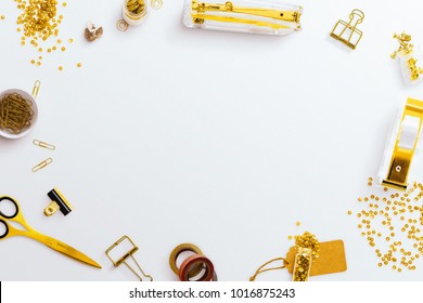 Desktop Flatlay Hero Image, With Gold Stationery Accessories, Stapler And Scissors. Circular Layout With Central Negative Space On A White Desk Background.