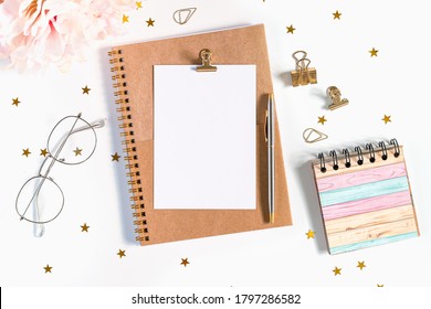 Desktop mock up planner. Flat lay of white working table background with peonies putting on it. Top view glasses, flower, golden paper binder clips, blank greeting card, craft Notebook and pen. - Powered by Shutterstock