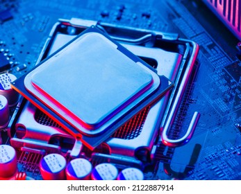 The desktop of the processor lies with the contacts up on the motherboard of a personal computer. Neon lighting. Technological background. Repair, network connection, computer components.