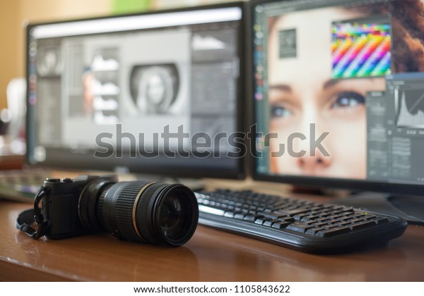 Desktop with two monitors, a keyboard, a\
camera, a diary, a palette for a designer, a retoucher, a\
photographer. With the image of the model on the monitors in\
special programs for\
retouching.