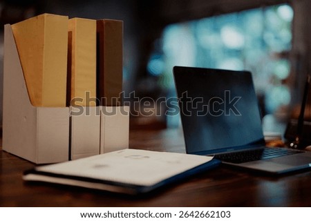 Desktop view with file holders, documents, and a laptop, representing structured office work and document management.