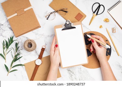 Desktop With Woman Hands Holding Clipboard And Recyclable Office Supplies. Home Office, Social Media Blog, Schedule, Planning Mockup. Flat Lay, Top View