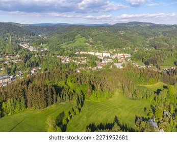 Desna v Jizerskych horach town in the middle of green hills of Jizera mountains on sunny summer day. Czech Republic. Aerial view from drone.