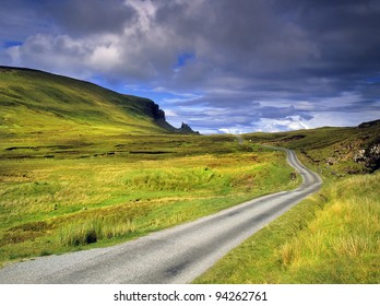 a desolate country road across moorland on the isle of syke with the quiraing in the distance - the isle of skye in Scotland, Great Britain UK