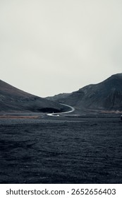 A desolate, winding road cutting through the harsh volcanic landscape of Iceland, evoking solitude and otherworldliness.
