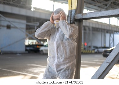 Despair Healthcare Worker In White Covid Protective Overalls.Tired Male Caucasian Doctor Grabs His Head Cower In Depression During Coronavirus Pandemic Paramedic Overworked Cry Covered Face With Hands