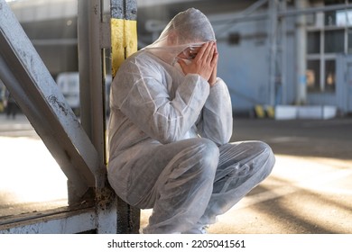 Despair Healthcare Worker In White Covid Protective Overalls.Tired Male Caucasian Doctor Grabs His Head Cower In Depression During Coronavirus Pandemic Paramedic Overworked Cry Covered Face With Hands