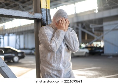 Despair Healthcare Worker In White Covid Protective Overalls.Tired Male Caucasian Doctor Grabs His Head Cower In Depression During Coronavirus Pandemic Paramedic Overworked Cry Covered Face With Hands