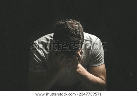 despair, man holding his head in his hands sitting on floor black and white portrait