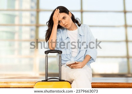 Despaired unhappy millennial european woman with suitcase and passport, suffers from late for transport, sit on train station or airport. Problems and stress, travel mistake emotions