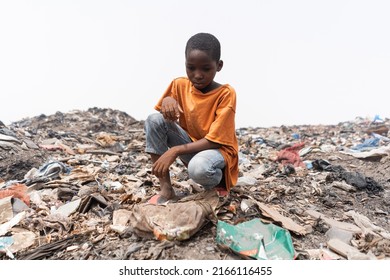 Despairing African Child Sitting On A Garbage Dump, Looking At The Plastic Waste. Environmental Justice Concept.