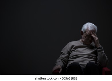 Despairing senior man on a dark background - Shutterstock ID 305651882