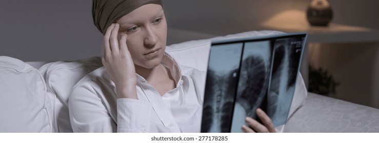 Despairing woman with brain cancer looking at x-ray photo