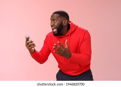 Desparate angry pissed african-american irritated man yelling smartphone look angry phone display gesturing dismay anger, furious lose last level hard game, standing bothered outraged