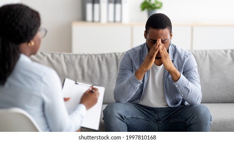 Desperate black man suffering from nevrous breakdown or depression, having session at psychologist's office, panorama. Stressed male patient meeting with therapist, receiving professional assistance - Shutterstock ID 1997810168