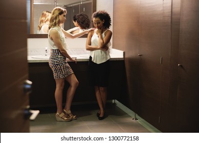 Desperate Business Woman In Office Bathroom, Crying For Bad News And Hostile Work Environment. A Young Friendly Colleague Is Supporting And Listening To Her.