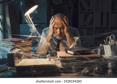 Desperate Businessman Sitting At Desk In His Abandoned Office: Business Failure And Financial Crisis Concept