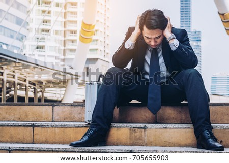 Desperate businessman sitting hopelessly on stair floor in central business district due to unemployment. Concept of failure, desperation, unemployment and business depression.