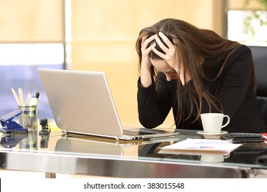 Desperate businesswoman on line worried after bankruptcy in front of a laptop with her hands in the head at office