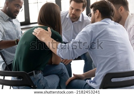 Desperate crying girl sharing sad experience with group mates on psychological support meeting. Diverse team of counselor patients giving help and comfort to depressed member. Mental health concept
