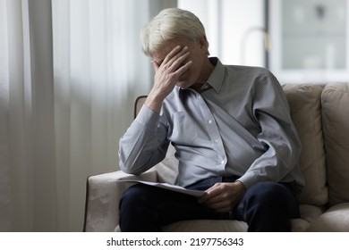 Desperate depressed senior elder man getting bad shocking news from paper documents, sitting on sofa at home, covering face with hand, receiving concerning medical result, bankruptcy notice - Powered by Shutterstock