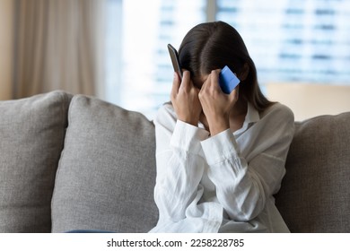 Desperate frustrated bank client woman facing scam, overspending, problems with online payments, blocked credit card, bankruptcy, holding smartphone, touching head, covering face