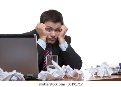 Desperate, frustrated man sitting with paperwork at desk in office. Isolated on white background.