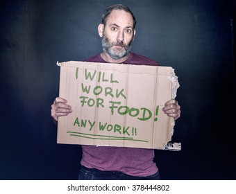 Desperate Man Holding A Cardboard Sign Looking For A Job In His Hands, Will Work For Food