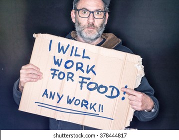 Desperate Man Holding A Cardboard Sign Looking For A Job In His Hands, Will Work For Food