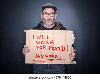 Desperate Man Holding A Cardboard Sign Looking For A Job In His Hands, Will Work For Food