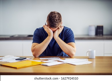 Desperate Man Leaning On Table And Holding Head In Hands Because He Have No Money To Pay Bills.