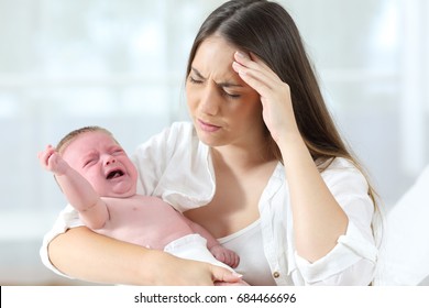 Desperate mother holding her angry baby crying 