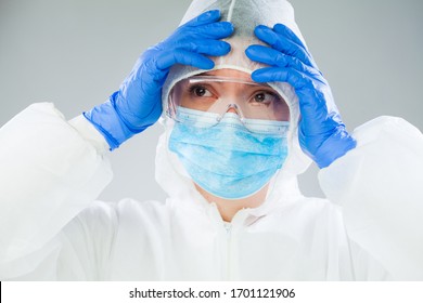 Desperate NHS UK medical EMS worker in white protective suit,blue surgical mask latex gloves safety goggles,Coronavirus COVID-19 pandemic crisis causing protective personal equipment supply shortage