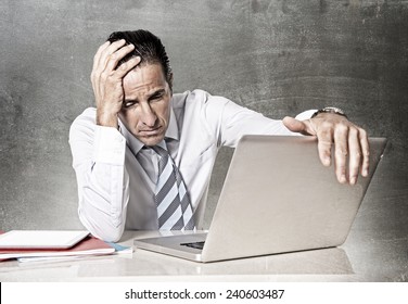 Desperate Tired Senior Businessman In Crisis Working On Computer Laptop At Office Desk In Stress Under Pressure Facing Work Problems On Grunge Studio Edition