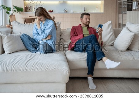 Desperate unhappy upset woman in stress crying, thinking of divorce. Indifferent husband addicted to mobile phone playing games, scrolling internet social networks, looks into smartphone ignoring wife