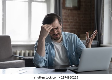 Desperate Upset Laptop User Man Sitting At Paper Bills, Documents, Calculator On Table, Touching Head, Feeling Frustrated, Stresses About Lack Of Money, Bankruptcy, Financial Loss