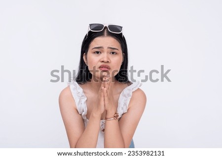A desperate and vulnerable woman begging for help and protection from someone. A damsel in distress pleading with clasped hands and submissive eyes. Isolated on a white background.