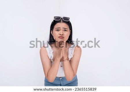 A desperate and vulnerable woman begging for help and protection from someone. A damsel in distress pleading with clasped hands and submissive eyes. Isolated on a white background.