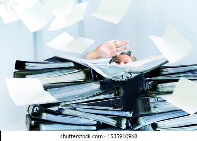 desperate woman behind high stacks of ring binders and lots of papers are flying around in the office, concept of excessive demands and increasing work in business, selected focus, motion blur