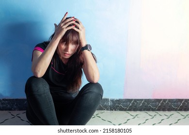 Desperate Woman In Depression Sits Against The Wall With Her Head Down On Her Knees. Concept Of Mental Problems And Mental Health.