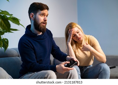 Desperate Woman Sitting Next To Her Husband, He Is Playing Video Games All Day Long