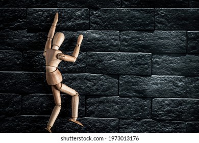 desperate wooden mannequin climbing a dark wall - Powered by Shutterstock