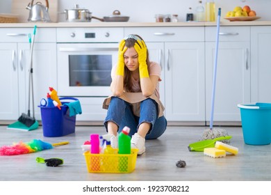 Desperate Young Housewife Tired From Domestic Duties Grabbing Her Head On Floor At Kitchen, Full Length Portrait. Millennial Woman Feeling Exhausted From Housework. OCD Concept