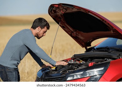 Desperate young man with broken down car in the middle of the road, dead battery