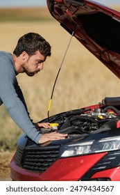 Desperate young man with broken down car in the middle of the road, dead battery